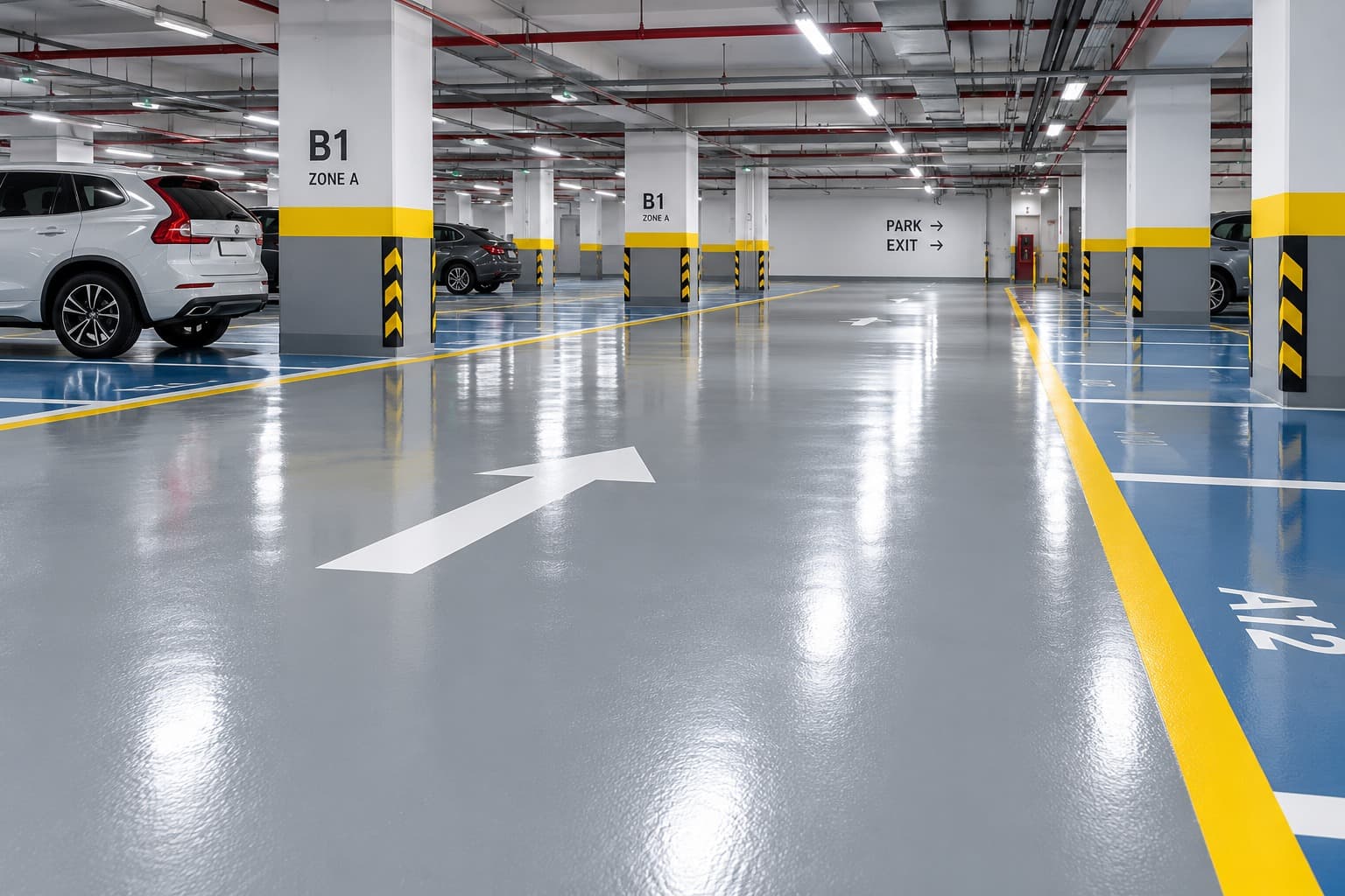A finished car park deck with grey epoxy coating, yellow and blue directional markings, hazard-striped columns and parked cars.